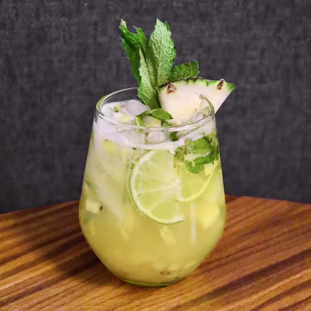 Drinks XXL Pineapple Mojito cocktail garnished with lime, mint, and a pineapple wedge.