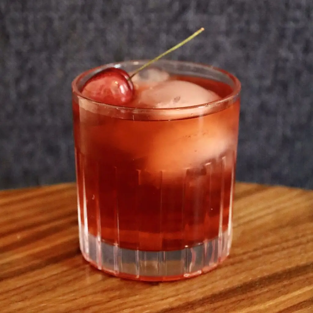 Drinks XXL Cherry Old Fashioned cocktail in a glass with ice and cherry garnish.