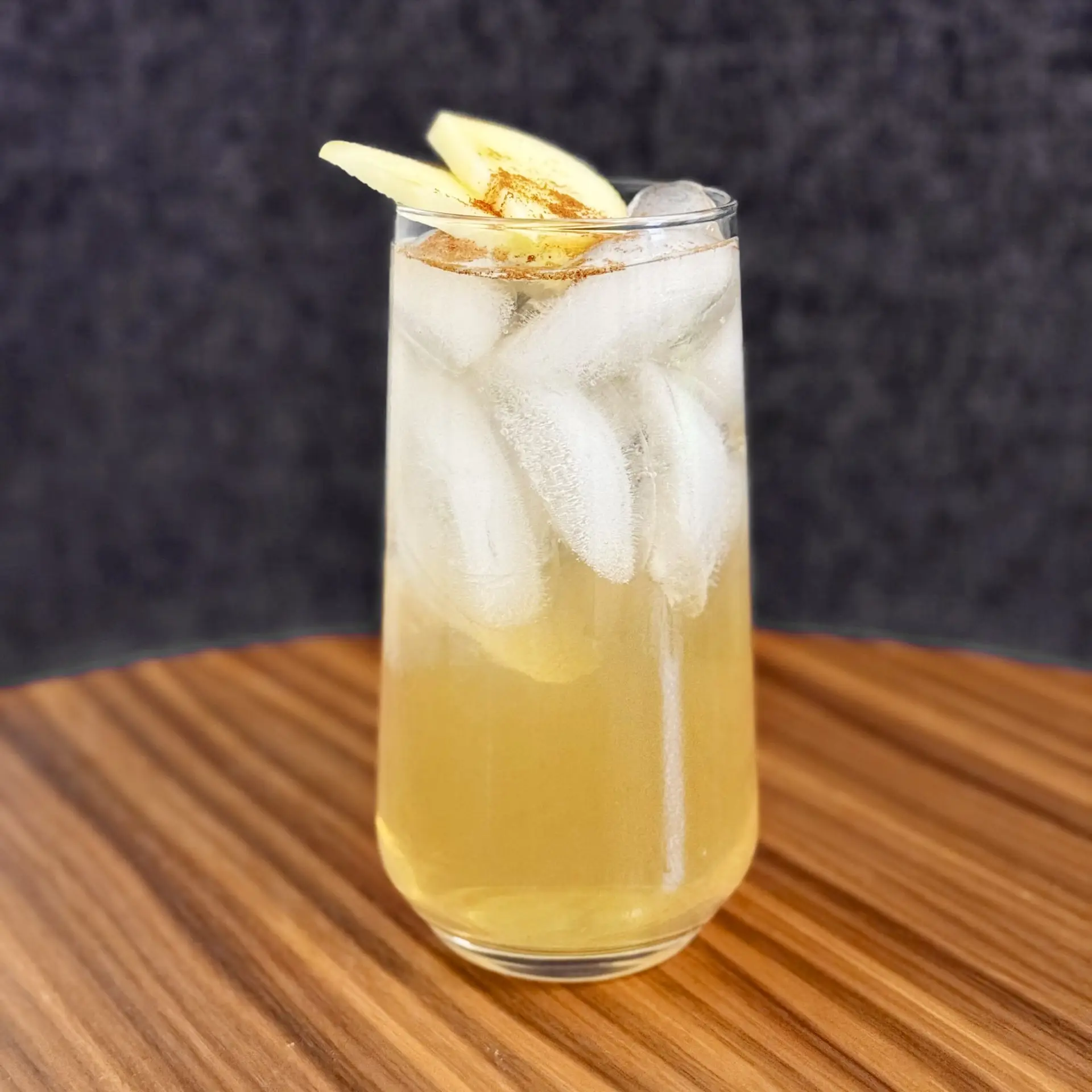 Drinks XXL Apple Cinnamon Fizz cocktail with ice, apple slices, and cinnamon garnish.